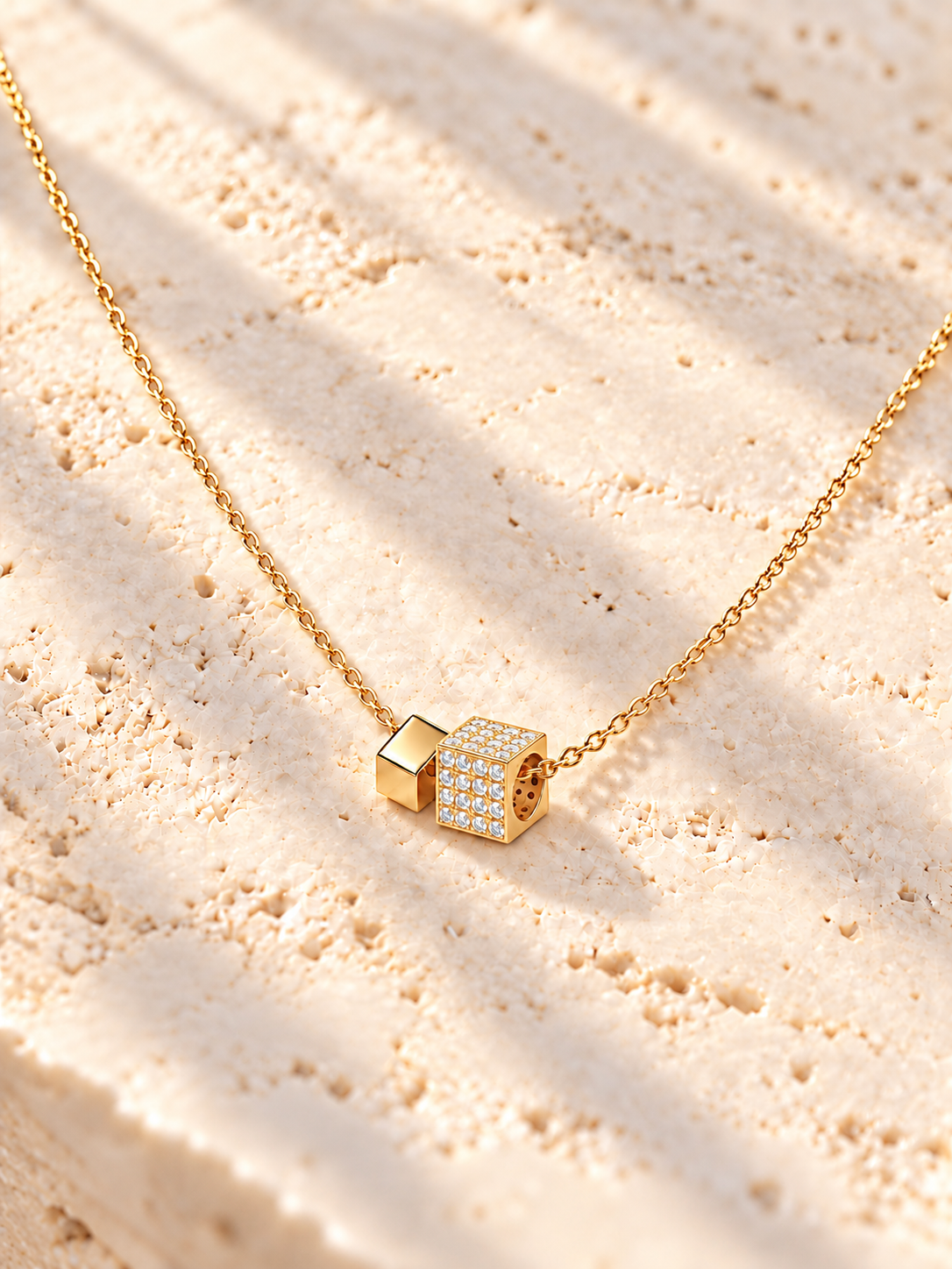 Collier Éclat cubique finition dorée avec un cube pavé de zircons et un petit cube lisse