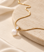 Gros plan du pendentif perle et détail scintillant du collier DIVINE