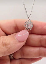 Détail du pendentif rose Rosy Glow tenu entre les doigts